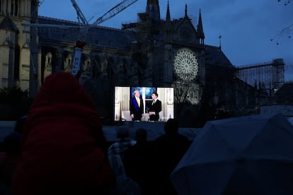 A screen in front of Notre Dame Cathedral in Paris shows images of the meeting between Donald Trump and Emmanuel Macron.