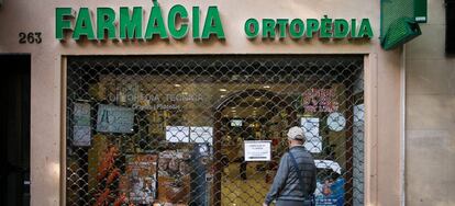 Un hombre lee un cartel en una farmacia de guardia en Barcelona.
