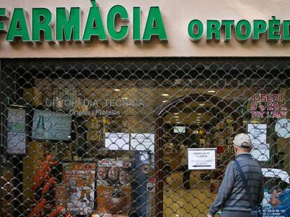 Un hombre lee un cartel en una farmacia de guardia en Barcelona.