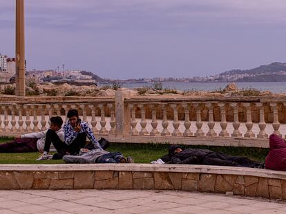 Varios Jóvenes descansan en un jardín próximo al paseo marítimo de la ciudad de Castillejos (Fnideq en árabe), en Marruecos. Al fondo se observa la ciudad de Ceuta.