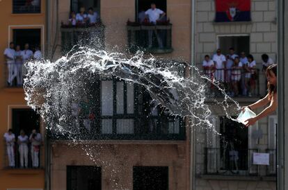 Una mujer lanza agua al público asistente al chupinazo en la plaza del Ayuntamiento de Pamplona.