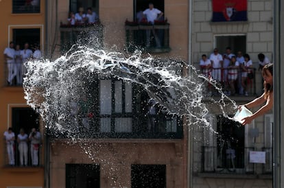 Una mujer lanza agua al público asistente al chupinazo en la plaza del Ayuntamiento de Pamplona.