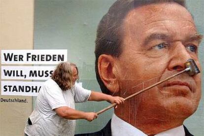 Un hombre pega un cartel electoral del canciller Schröder en Dusseldorf.