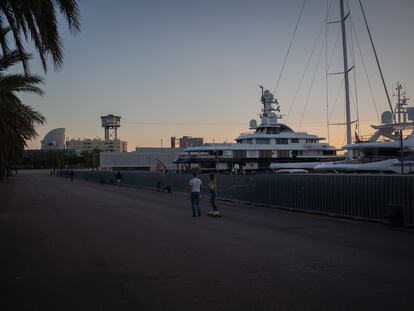 Dos jóvenes pasean al lado de varios barcos en Barcelona.