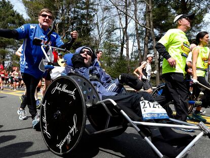 Rick Hoyt, center, is pushed by his father Dick, left, along the Boston Marathon course, April 15, 2013, in Wellesley, Mass. Hoyt, who with his father pushing his wheelchair became a fixture at the Boston Marathon and other races for decades, has died. He was 61. Hoyt died of complications with his respiratory system, his family announced on Monday, May 22, 2023. (AP Photo/Michael Dwyer, File)