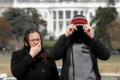 Dos turistas se protegen de los vientos fuertes, que continúan en Washington.