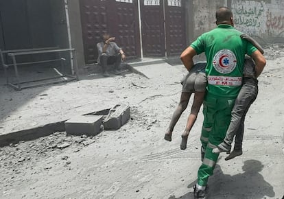 Un miembro de los servicios de emergencia transporta a dos víctimas de los bombardeos en casas de Ciudad de Gaza, este sábado.