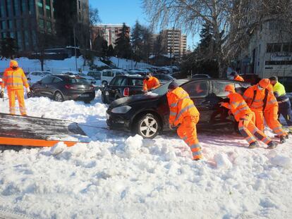 Los servicios de emergencia retiran un vehículo atrapado en la nieve, en Madrid. 