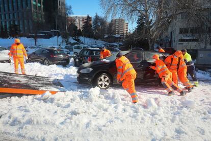 Los servicios de emergencia retiran un vehículo atrapado en la nieve, en Madrid. 