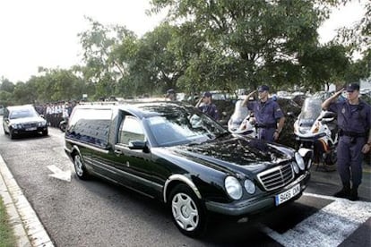 Agentes de policía saludan al paso de los coches fúnebres que trasladan a León a las dos jóvenes asesinadas el martes.