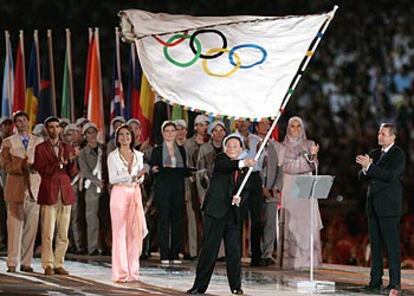 El alcalde de Pekín, Wang Qishan, recibe la bandera olímpica en presencia de Jacques Rogge, a la derecha, presidente del COI, e Hicham El Guerruj, a la izquierda.