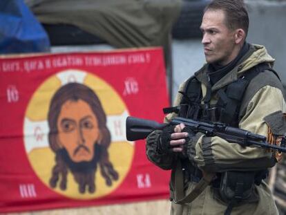 Um rebelde ucraniano diante de uma bandeira do Batalhão Ortodoxo Russo.
