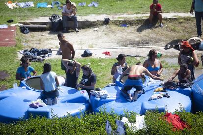 Um grupo de migrantes toma banho em tambores de água em 'cidade Palito', como foi apelidado o albergue na Cidade do México.