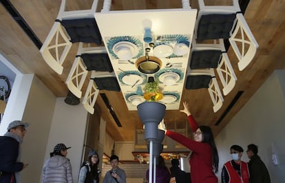 A visitor poses inside an upside-down house created by a group of Taiwanese architects at the Huashan Creative Park in Taipei, Taiwan, Tuesday, Feb. 23, 2016. With a build price of $600,000 and over 300 square meters (3,230 square feet) of floor space filled with real home furnishings, the upside-down house will continue to be on display to visitors until July 22. (AP Photo/Wally Santana)