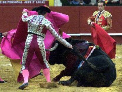 Un peón intenta levantar al quinto toro, invlálido como toda la corrida, tirándole del rabo.