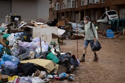 En la imagen, un hombre tira la basura en una montaña de bolsas en Paiporta, tras la falta de contenedores.