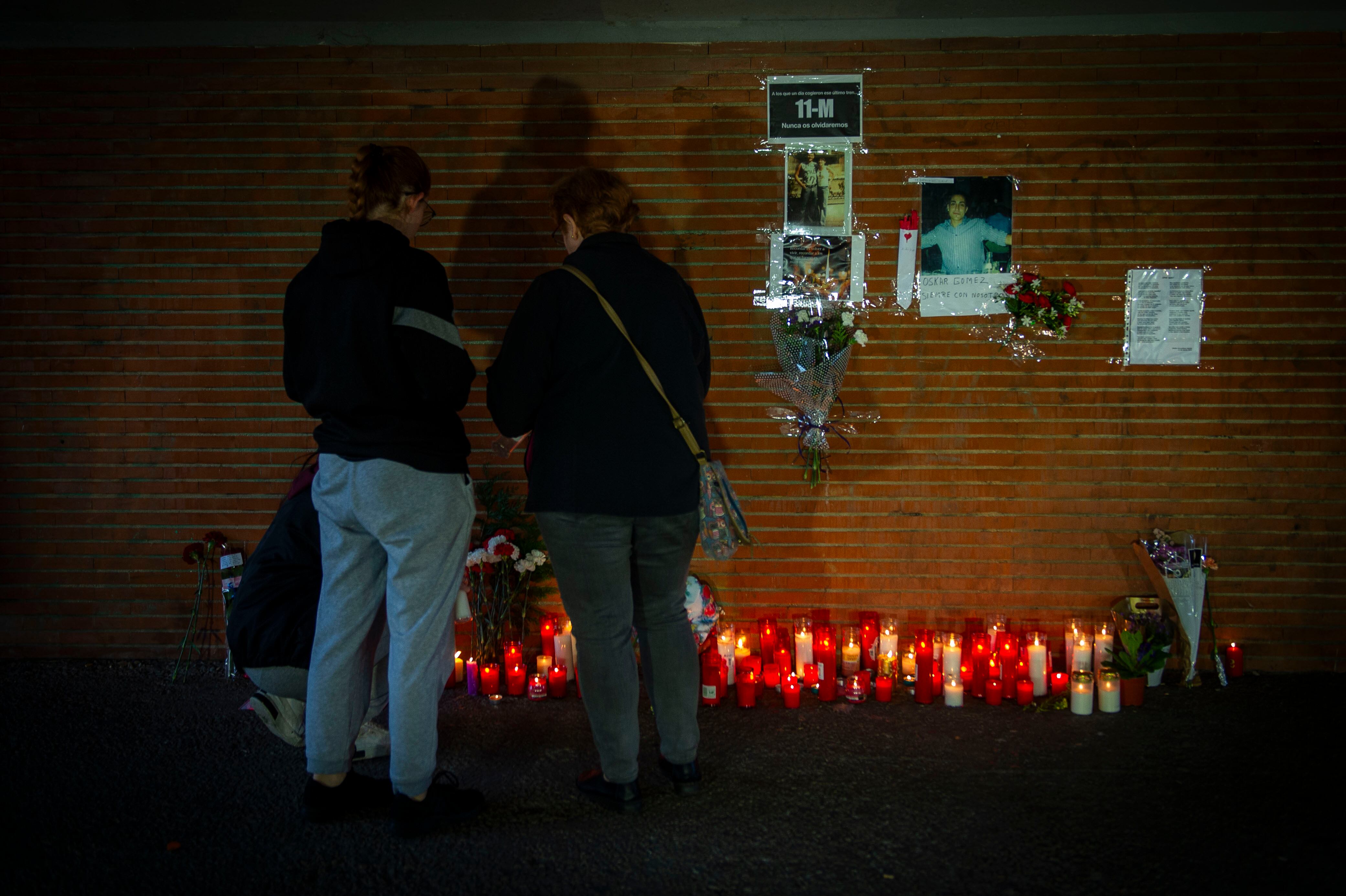 Varias personas colocan velas en homenaje a las víctimas del atentado del 11-M en la estación de Renfe de 'El Pozo', este lunes.