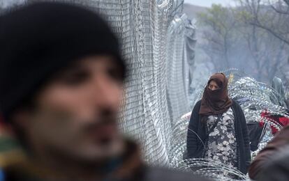 Mulher observa cerca que barra passagem de refugiados na região da Macedônia.