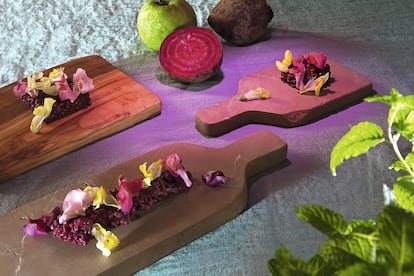 <p><b>TARTAR DE REMOLACHA CON FLORES</b></p> <p><b>Ingredientes. </b>Para cuatro personas: 100 gramos de remolacha cocinada a la sal, 50 gramos de manzanas reineta, 50 gramos de manzanas Granny Smith, 50 gramos de aguacate, 37,50 gramos de remolacha cocida, ½ cucharada sopera de vinagre de Módena, sal, pimienta, aceite de oliva. Para las flores: 20 gramos de pétalos de flores comestibles.</p><p><b>Elaboración. </b> 1. Para las remolachas a la sal: ponerlas en una bandeja honda y cubrir de sal gruesa. La introducimos en el horno a 180 grados durante una hora aproximadamente, dependiendo del tamaño de las remolachas. Para saber si están listas, las pincharemos con un cuchillo y si no oponen resistencia al clavar significará que están cocidas. Una vez hechas, las pelamos y guardamos la carne. 2. Para el tartar de remolachas: cortamos la remolacha cocida a la sal y las manzanas en brunoise pequeña de un milímetro. En el robot de cocina pondremos el aguacate sin la piel, la remolacha cocida, el vinagre de Módena, sal y pimienta. Lo trituramos y emulsionamos la crema con un chorrito de aceite. La mezcla tiene que quedar bien triturada. Juntamos la crema con la brunoise de remolacha y manzana y reservamos. Servimos muy frío, con los pétalos de las flores por encima.</p> <p>Las tablas usadas en esta receta son de Con Alma Design. Están elaboradas con madera de árboles caídos y podados y con piedra de canteras de Mallorca (desde 35 euros la unidad).</p>