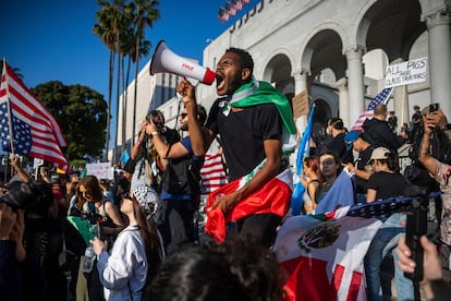 Un hombre grita, megáfono en mano, durante una protesta frente al Ayuntamiento de Los Ángeles.