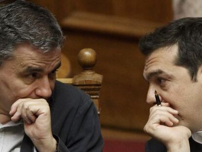 Euclides Tsakalotos (izquierda) habla con el primer ministro Alexis Tsipras durante la aprobaci&oacute;n de las subidas de impuestos reclamadas por la troika.