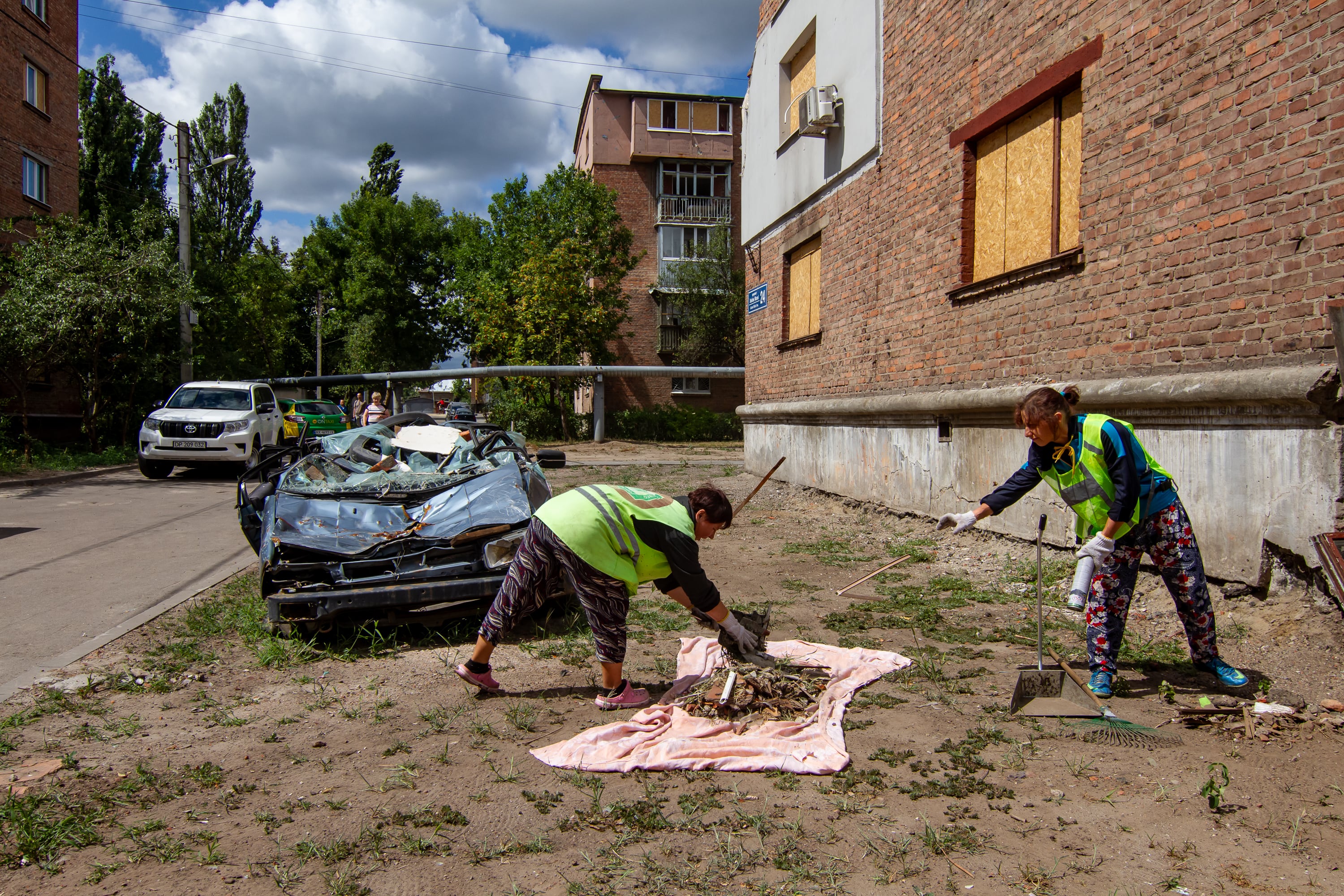 Dos mujeres recogen escombros y otros restos dejados por el bombardeo ruso que en mayo mató a nueve personas en este barrio de Járkov, el 30 de julio.