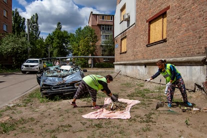 Dos mujeres recogen escombros y otros restos dejados por el bombardeo ruso que en mayo mató a nueve personas en este barrio de Járkov, el 30 de julio.