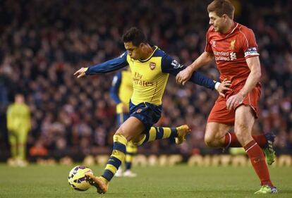 Alexis se prepara para chutar ante Gerrard, del Liverpool.