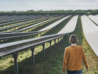 Una mujer camina entre los paneles de una instalación fotovoltaica.