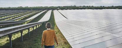 Una mujer camina entre los paneles de una instalación fotovoltaica.