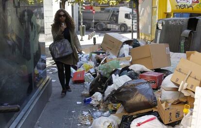 A woman walks past garbage piled up in Madrid&#039;s Amaniel street on Monday.