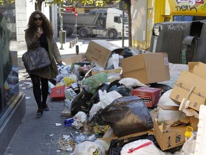 A woman walks past garbage piled up in Madrid&#039;s Amaniel street on Monday.