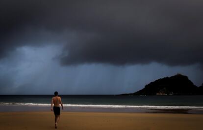 Un joven se dirige hacia el agua en la playa de Ondarreta de San Sebastián.