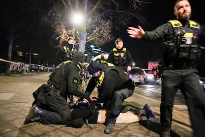 Police officers stop a man near the memorial, this Friday.