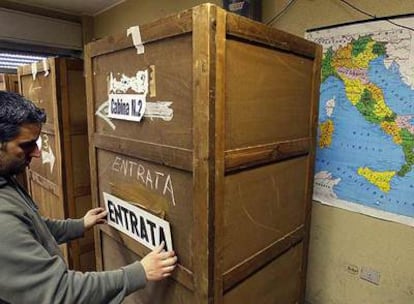 Un hombre coloca un cartel sobre una cabina en un colegio electoral de Roma, para las elecciones generales de hoy.