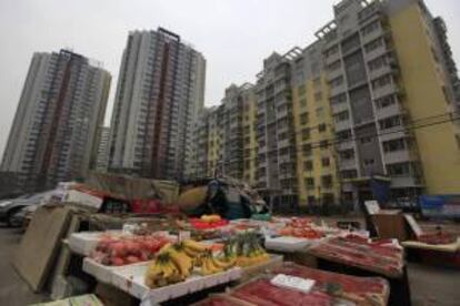 Una vendedora callejera vigila su puesto cerca de varios bloques de apartamento en Pekín (China). EFE/Archivo