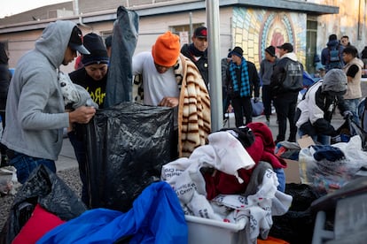Migrantes buscan ropa entre los donativos de un refugio, en El Paso, Texas.
