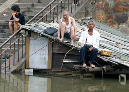 Dos habitantes de Yueyang aprovechan las inundaciones para pescar.