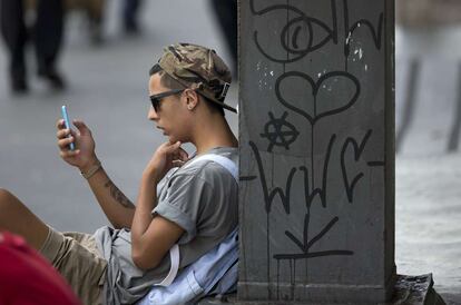 Jovem consulta celular em São Paulo.