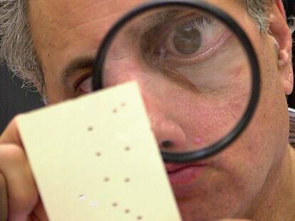 Un empleado del condado de Broward, Florida, examina una papeleta electoral durante el recuento tras las elecciones de noviembre de 2000.