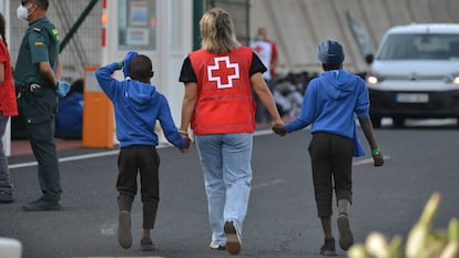 Una trabajadora de la Cruz Roja acompaña a dos de los menores que llegaron en un cayuco a El Hierro en septiembre.