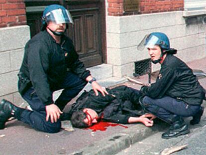 Dos policías atienden a su compañero David Nivel, herido en los disturbios de Lens en el Mundial 98.