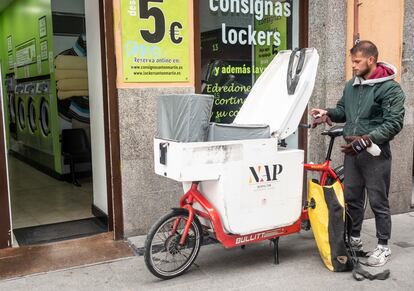 Un 'rider' recoge unas sábanas en una lavandería del centro de Madrid para distribuirla por varios pisos turísticos y hostales.