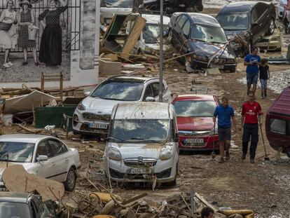 Varios vecinos observan los daños causados en una calle de Tafalla (Navarra) donde decenas de vehículos han quedado inmovilizados tras ser arrastrados por las lluvias.