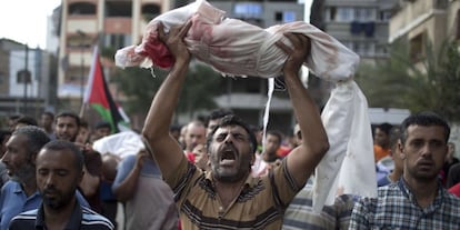 Um homem levanta o corpo de um menino de um ano, morto na quinta-feira no ataque a uma escola da ONU em Gaza.