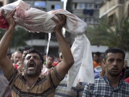 Um homem levanta o corpo de um menino de um ano, morto na quinta-feira no ataque a uma escola da ONU em Gaza.