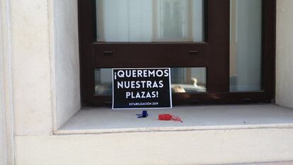 Uno de los carteles de reivindicación de los 'opositores fantasma' de Andalucía, para reclamar a la Junta que publique sus destinos definitivos, junto a varios silbatos, colocados en una ventana tras una manifestación en Sevilla.  / M. G.