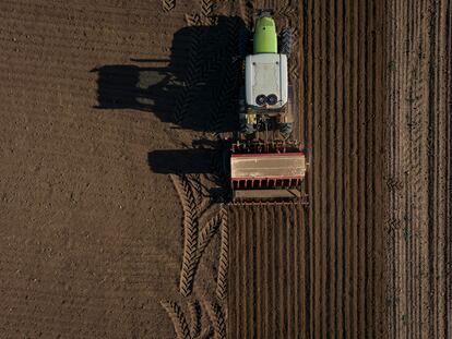Un agricultor pasa la sembradora con un tractor en un campo de cultivo de secano.