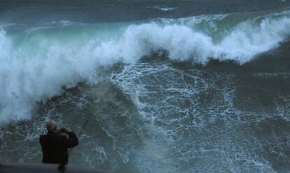 Un turista graba las olas esta tarde en la costa de Muxía, en una jornada en la que Galicia se encuentra en alerta roja por un temporal de vientos fuertes, lluvias persistentes e intenso oleaje, con olas que pueden llegar a los once metros. 