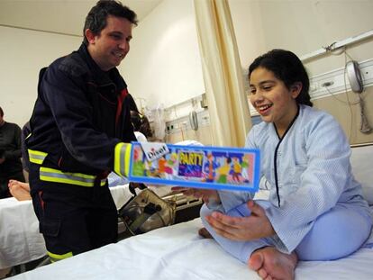 Kaltuma, de 11 años, recibe la visita de los bomberos en el hospital Gregorio Marañón.